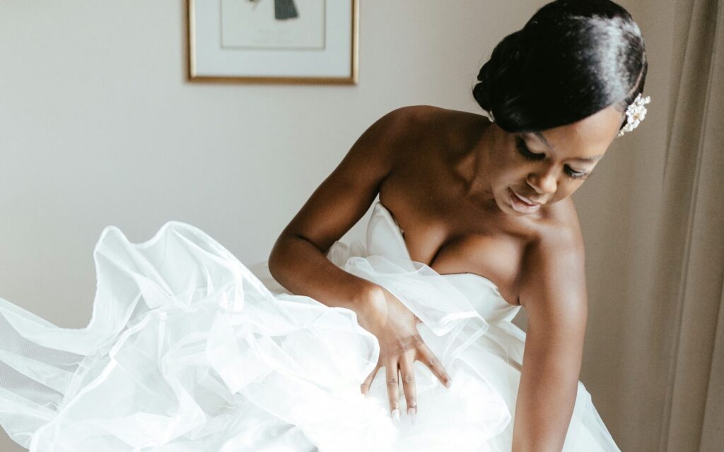 Reflecting on her emotions during a bridal dress shopping experience. Her expression conveys a mix of excitement and anticipation, surrounded by beautiful gowns in a bridal boutique.